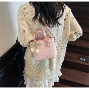 Pink and white checkered bucket bag with tulip pendant worn by model on stairs