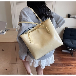 Détail d'un sac cabas crème à motif crocodile porté à l'épaule pour un look quotidien