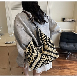 Close-up of woven tote bag with contrast geometric pattern and decorative wooden beads