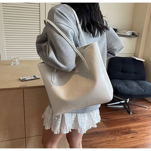 Vue détaillée d'un sac cabas blanc à texture crocodile porté par un mannequin chic
