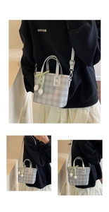 Close-up of a grey plaid bucket bag with tulip pendant and adjustable crossbody strap
