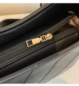 Close-up of smooth gold metal zipper on black quilted leather tote bag for women