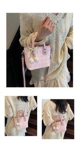 Close-up of pink checkered bucket bag with white tulip charms and green silk bow detail
