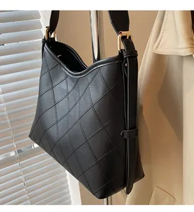 Detail of black quilted shoulder bag with gold metal buckle and adjustable strap