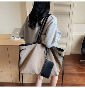Detail of canvas tote bag with leather trim and small pouch in a workspace setting