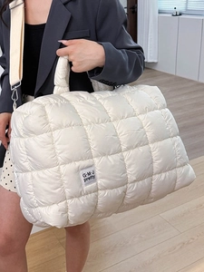Borsa tote trapuntata bianca con consistenza soffice e ampia tracolla indossata da modella