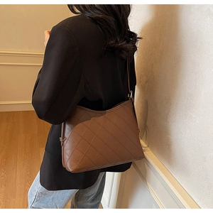 Detail of dark brown quilted leather tote bag with elegant diamond stitching and strap