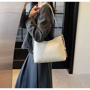 Detail of quilted diamond pattern and stitching on off-white faux leather tote bag