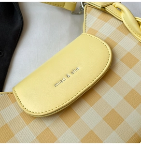 Détail d'un sac à carreaux avec logo argenté estampé et texture de poignée tressée