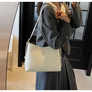 Close-up of beige quilted tote bag with diamond stitching shown in a mirror reflection