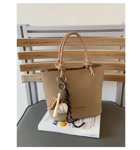 Detail of lychee pattern leather bucket bag with knotted handle and baseball charm