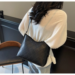 Close-up of black quilted shoulder bag with synthetic leather and elegant stitching detail