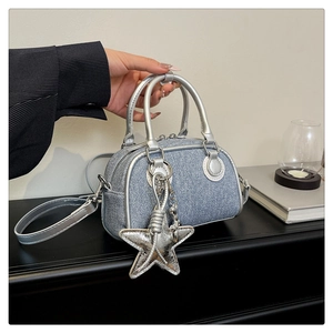 Détail du sac bowling en denim avec garniture argentée et pendentif en forme d'étoile