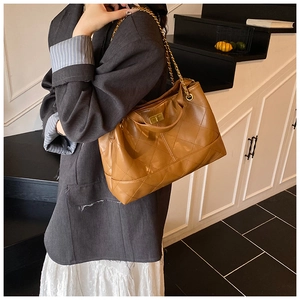 Detail showing the brown quilted leather texture and gold chain strap of this shoulder bag