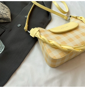Détail du sac bandoulière à carreaux jaune et beige avec poignée tressée et rabat