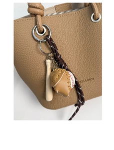 Detail view of a baseball glove and bat bag charm hanging on a lychee pattern bucket bag