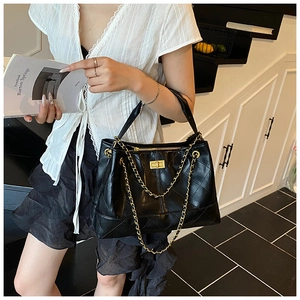 Detailed view of black quilted leather tote bag with gold chain strap and turn-lock