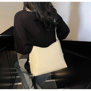 Detail of cream quilted tote bag with diamond stitching shown on a shoulder