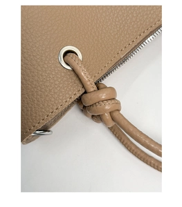 Macro detail of khaki litchi grain leather bucket bag with silver hardware and knotted strap