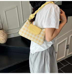 Détail du sac sous l'aisselle à carreaux jaunes avec bandoulière tressée sur un mannequin