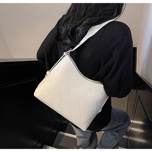 Close-up of beige quilted tote bag with diamond stitching and adjustable strap on model