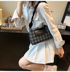 Gros plan du sac à motif vichy avec rabat en cuir et bandoulière tressée