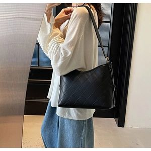 Detail of black quilted leather shoulder bag featuring rhombus stitching and side buckle