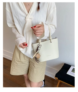 Détail du sac seau en cuir litchi crème avec breloques de baseball et batte de sport