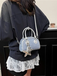Sac bowling en denim bleu avec charms étoile porté par un mannequin au style épuré