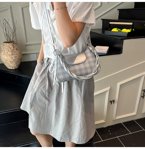 Détail du sac à bandoulière argenté à carreaux avec chaîne torsadée et texture de tissu