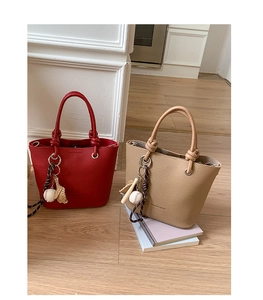 Detail of red and beige pebble leather bucket bags with knotted ropes and baseball charms
