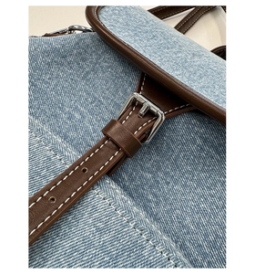 Detail view of denim canvas backpack with leather straps and silver metal buckles