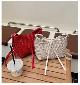 Détails de sacs à bandoulière en cuir tressé rouge et beige sur une table en bois