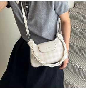 Détail du sac à carreaux crème avec poignée tressée et gaufrage de la marque