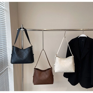 Three minimalist quilted tote bags in black, brown and cream displayed on a hanger