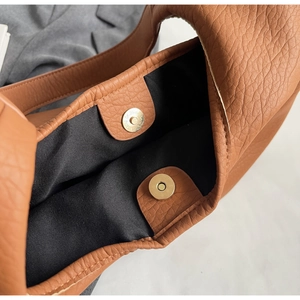 Gros plan d'un sac cabas en cuir marron grainé avec un fermoir magnétique doré
