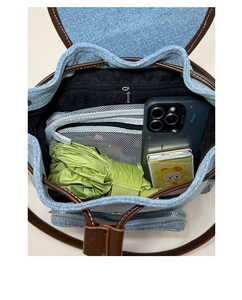 Internal view of denim backpack showing drawstring closure and zipper pocket storage