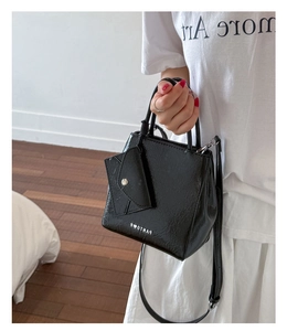 Detail of black glossy handbag featuring silver hardware and a detachable small pouch