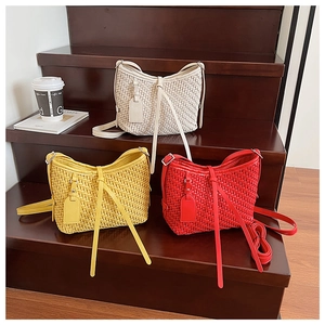 Gros plan de sacs seaux tressés en blanc, jaune et rouge sur marches en bois
