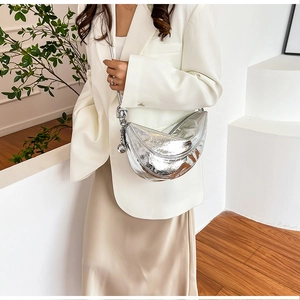 Close-up of a silver metallic crescent bag with pleated texture and stylish ball charm