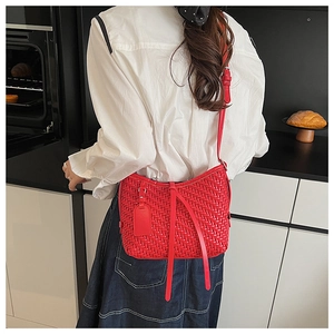 Détail du sac bandoulière en cuir tressé rouge avec texture précise et longues lanières