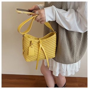 Gros plan du sac bandoulière tissé jaune vif avec forme demi-lune et texture fine