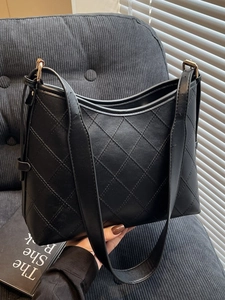 Minimalist black quilted tote bag with diamond stitching and adjustable wide shoulder strap