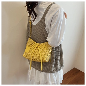 Détail du sac à bandoulière tressé jaune montrant le tissage et la sangle ajustable