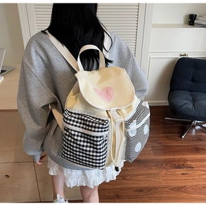 Detail of canvas backpack featuring heart embroidery and checkered patchwork pockets