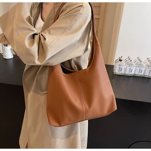 Gros plan du sac cabas en cuir marron à motif litchi montrant coutures et texture