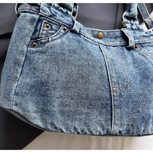 Dettaglio di borsa tote in denim vintage con rivetti in metallo e cuciture arancioni