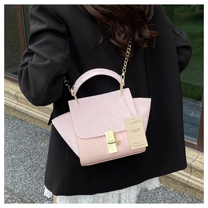Close-up of pink faux leather crossbody bag with crocodile texture and gold chain strap