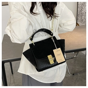Detail of matte black wing handbag with gold twist lock and crocodile texture flap