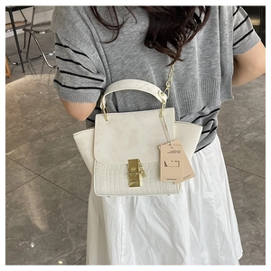 Detail of cream winged handbag with crocodile texture and gold clasp on a model